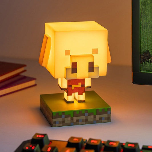 The Minecraft Piglin Icon Light by Paladone glows warmly on a blocky base near a computer monitor and keyboard, with two notebooks in the background. Perfect for any Minecraft collectible setup.