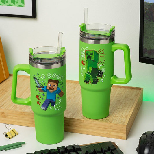 Two large green Minecraft Insulated Cup And Straw Steve & Creeper by Paladone sit on a wooden surface. Each cup features Minecraft graphics—Steve with a sword or a Creeper—and comes with a versatile lid and straw.