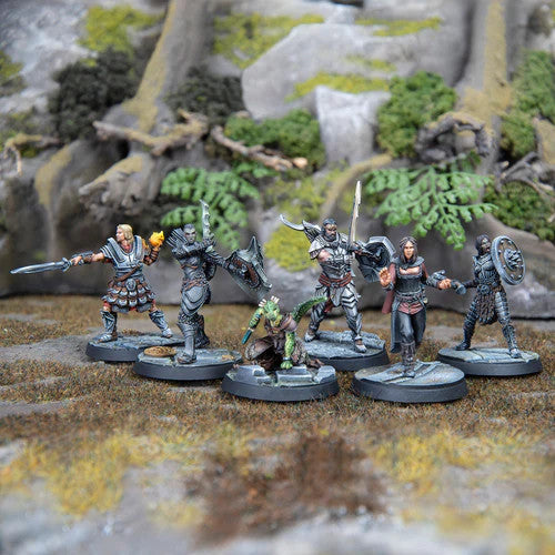 Six detailed miniatures from Modiphius The Elder Scrolls Call To Arms Adventurer Fortune Hunters, including armored warriors, a robed figure, and an elf, stand ready for Skyrim-inspired quests on rocky terrain.